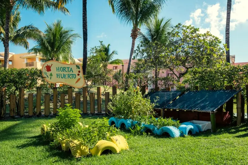 Horta do resort com placa e canteiros feitos de pneus coloridos