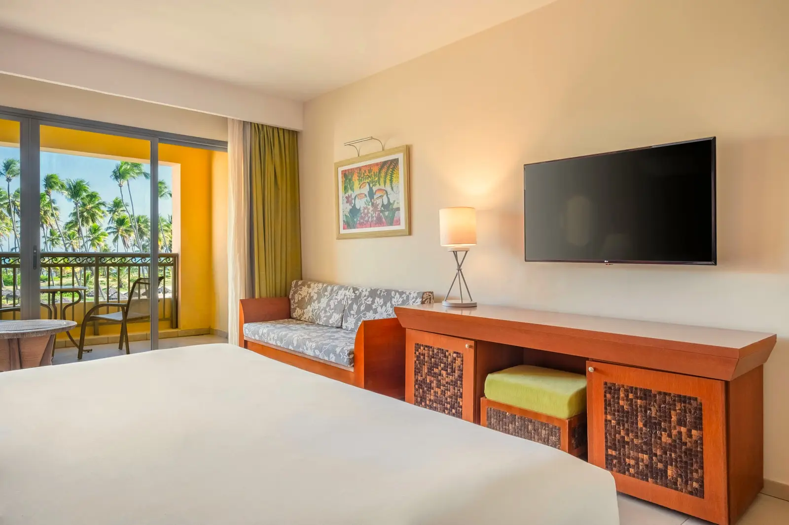 Junior suite com cama, sofá, smart TV e móvel de madeira